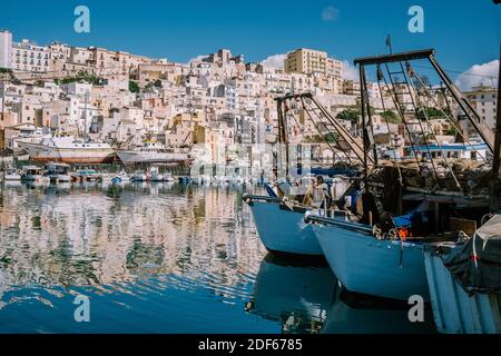 Sciacca Sicilia ottobre 2020, barche da pesca e persone riparano reti nella colorata città di Sciacca che si affaccia sul suo porto. Provincia di Agrigento, Sicilia. Foto di alta qualità Foto Stock