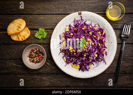 Insalata di insalata di cavolo fresco fatta di cavolo rosso e bianco grattugiato e mais su sfondo di legno scuro, vista dall'alto Foto Stock