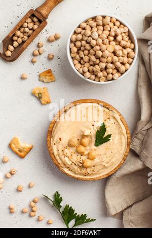 Flatlay Hummus in un piatto di legno e ceci crudi in una ciotola. Piatti di ceci, un piatto vegetariano. Foto Stock