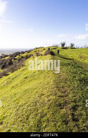 Gli escursionisti camminano lungo il bastione di una leggera collina in uniforme dell'Età del ferro su Ring Hill presso il punto di vista di Cotswold di Haresfield Beacon, Gloucestershire Foto Stock