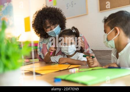 Insegnante con bambini che indossano maschera in classe prescolare durante pandemia del virus della corona - concetto di sanità e istruzione Foto Stock