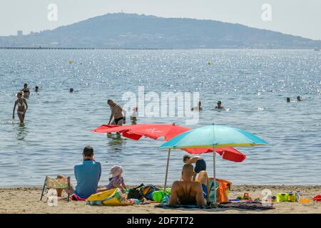 Francia, Herault, laguna di Thau, Meze, vacanzieri sotto un ombrellone su una spiaggia Foto Stock