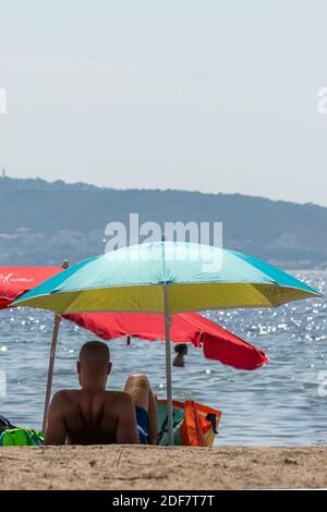 Francia, Herault, laguna di Thau, Meze, vacanzieri sotto un ombrellone su una spiaggia Foto Stock