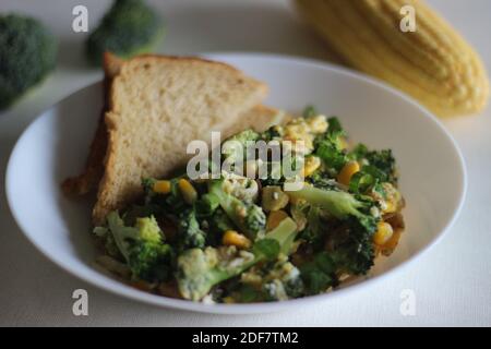 Uova strapazzate con broccoli, mais dolce e cipollotti, una colazione sana Foto Stock