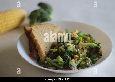 Uova strapazzate con broccoli, mais dolce e cipollotti, una colazione sana Foto Stock