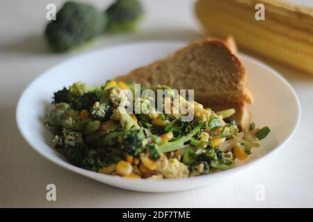 Uova strapazzate con broccoli, mais dolce e cipollotti, una colazione sana Foto Stock