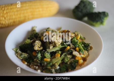 Uova strapazzate con broccoli, mais dolce e cipollotti, una colazione sana Foto Stock