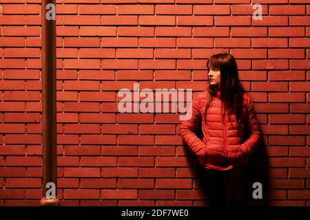 Croazia, Contea di Varazdin, Varazdin, donna appoggiata contro un muro di mattoni rossi Foto Stock