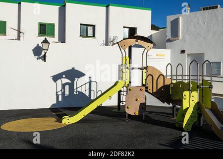 Parco giochi per bambini, scivolo e struttura per arrampicata getta un'ombra da allenamento sulla parete di un condominio a Santiago del Teide, Tenerife, Isole Canarie, SPAI Foto Stock