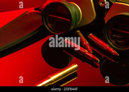 Binocoli militari e cartucce su sfondo a specchio Foto Stock