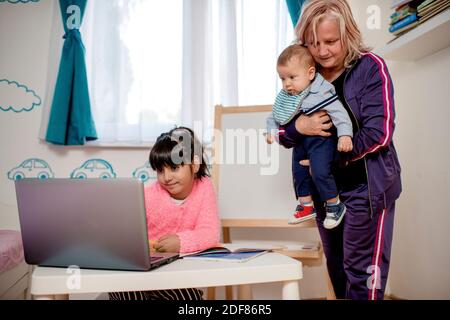 La ragazza della scuola sta studiando con la nonna. Scuola domestica. Formazione a distanza. Foto Stock