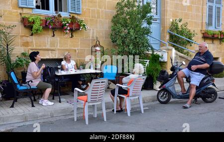 Amici, vicini si incontrano per chiacchierare in giro per il tavolo sul marciapiede esterno Foto Stock