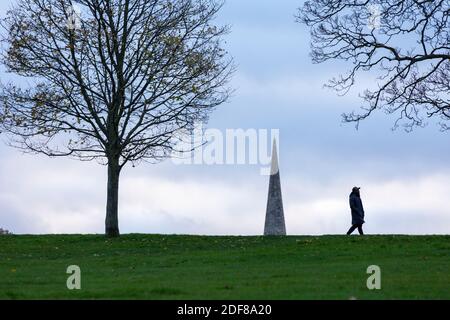 Una persona che cammina nel Brockwell Park con il campanile della chiesa della Santa Trinità sullo sfondo, Londra Foto Stock