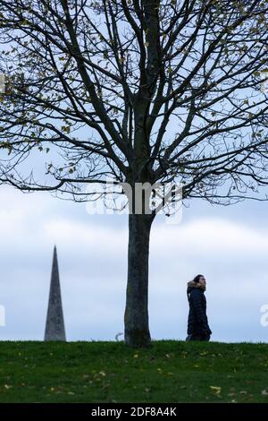 Una ragazza che cammina nel Brockwell Park con il campanile della Santa Trinità Chiesa sullo sfondo, Londra Foto Stock