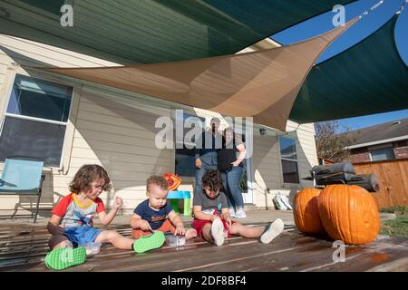 Nicole e Brandon Overton guardano i loro tre figli più giovani Greeley (pantaloni arancioni), 1, Saben (shorts blu), 4, e Kafry (shorts rossi), 6, giocare nel cortile della loro casa nel sud di Austin. Foto Stock