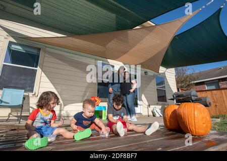 Nicole e Brandon Overton guardano i loro tre figli più giovani Greeley (pantaloni arancioni), 1, Saben (shorts blu), 4, e Kafry (shorts rossi), 6, giocare nel cortile della loro casa nel sud di Austin. Foto Stock