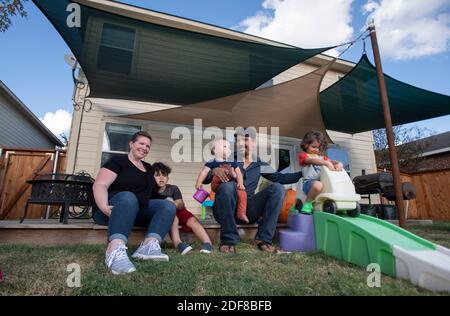 I genitori Nicole e Brandon Overton e la loro famiglia, Greeley (pantaloni arancioni), 1, Saben (shorts blu), 4, e Kafry (shorts rossi), 6, a casa loro nel sud di Austin. Foto Stock