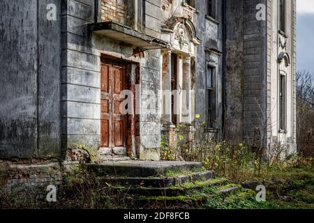 Portico di un vecchio palazzo con una scala in pietra e. una porta rossa Foto Stock