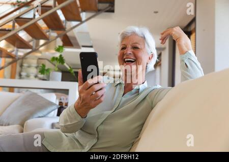 Felice donna caucasica anziana che ha videochiamata usando lo smartphone Foto Stock