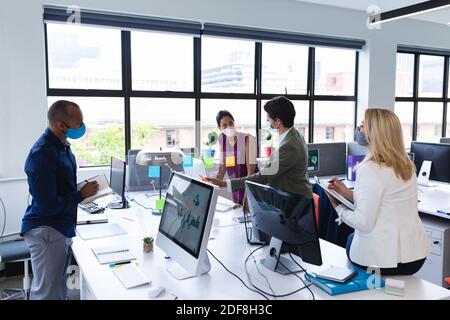 Uomini d'affari diversi e donne d'affari che indossano maschere di fronte che discutono in ufficio Foto Stock