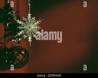 Brillante ornamento di Natale su sfondo rosso scuro sbiadito. Vacanze invernali artistiche, concetto di nuovo anno con spazio di copia. Foto Stock