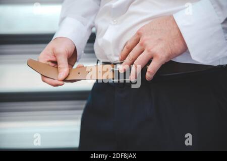 Prepara la mattina degli sposi, un uomo che mette su una cinghia Foto Stock