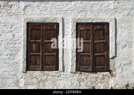 due finestre di legno chiuse sulla parete di a. Casa greca con le pareti intonacate di bianco lime Foto Stock