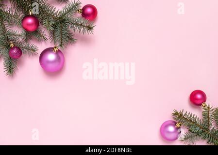 Composizione natalizia di rami di abeti e palle rosa su sfondo rosa pastello con spazio di copia per il testo. Natale e Capodanno. Foto Stock