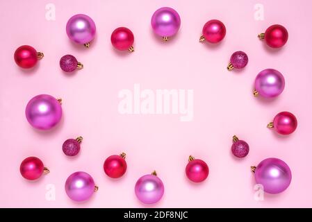 Cornice fatta di decorazione baubles Natale su sfondo rosa pastello con spazio copia per il testo. Vista dall'alto. Foto Stock