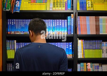 Un uomo esplora la sezione dei libri di viaggio di una libreria a Pechino, in Cina Foto Stock