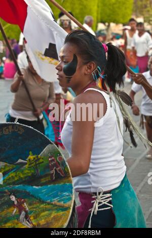 Una ragazza messciana con bandiera celebra durante il DIA DE LOS LOCOS (GIORNO DEI PAZZI) - SAN MIGUEL DE ALLENDE, GUANAJUATO, MESSICO Foto Stock