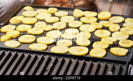 Patate tagliate a piccoli cerchi, condite con spezie, grigliate su griglia elettrica Foto Stock