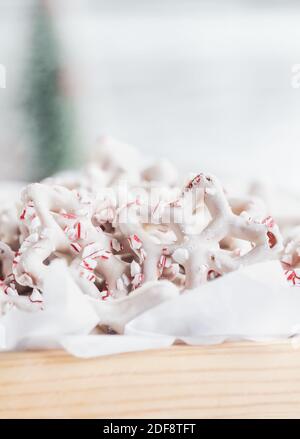 Prettzel ricoperti di cioccolato bianco o yogurt fatti in casa con pezzi di canna caramella schiacciata. Messa a fuoco selettiva con primo piano e sfondo sfocati. Foto Stock