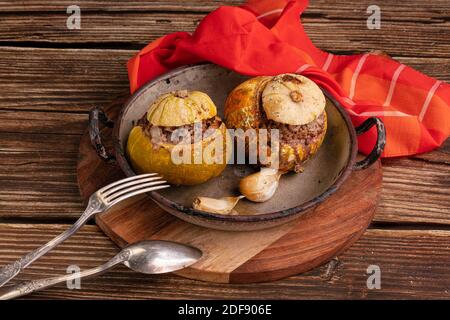 Giraumon o zucca turbata ripiena di carne in un vecchio piatto su un tavolo di legno Foto Stock