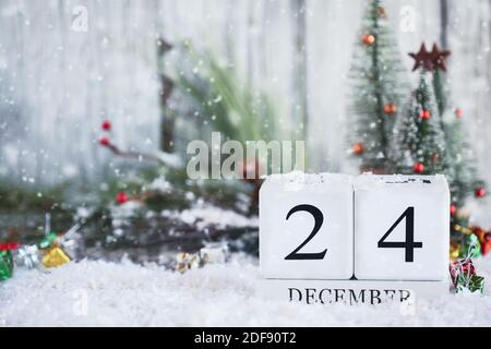 Vigilia di Natale. Blocchi calendario in legno bianco con data 24 dicembre e decorazioni natalizie con neve. Messa a fuoco selettiva con sfondo sfocato. Foto Stock