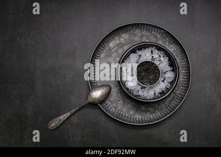 Caviale in una scatola di metallo su sfondo nero Foto Stock