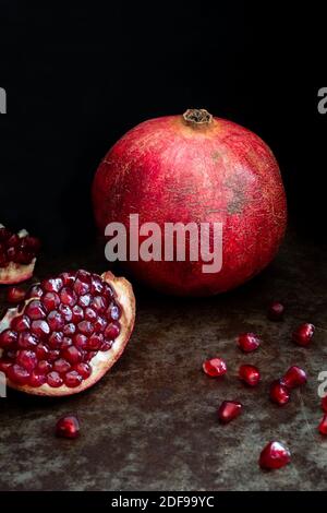 Melograno frutta intera e aperta su sfondo nero Foto Stock