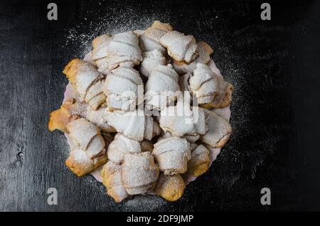 Biscotti fatti in casa sotto forma di bagel con marmellata di ripieno cosparso di zucchero in polvere su uno sfondo di legno. Messa a fuoco selettiva. Foto Stock