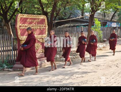 Giovani monaci portano la loro offerta bocce a un tempio - BAGAN, MYANMAR Foto Stock