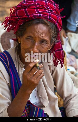 Una donna SHAN fuma un sigaro al mercato YWAMA sul modo di INDEIN - Lago Inle, MYANMAR Foto Stock