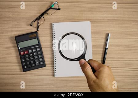 Vista dall'alto della lente di ingrandimento con supporto manuale sopra il blocco note Foto Stock