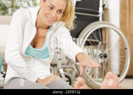 donna atleta sorridente e disabile che si allunga a casa Foto Stock