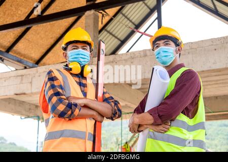 Due operai edili indossano maschere mediche, prevengono la diffusione Corona o Covid-19 indossare maschere presso il cantiere Foto Stock