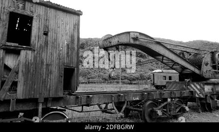 Vagone arrugginito e abbandonato fuori dalla ferrovia. Il carro marcio si trova in una foresta tropicale [colori bianco e nero] Foto Stock