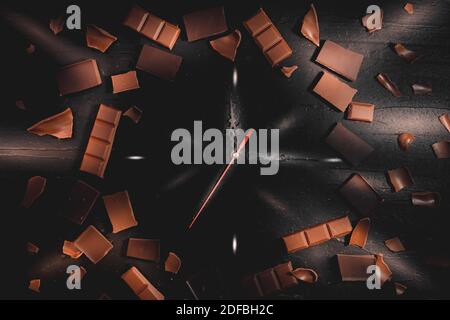 Tempo per il cioccolato. Foto creativa con fata come la luce. Carta da parati con orologio al cioccolato e vista dall'alto. Foto Stock