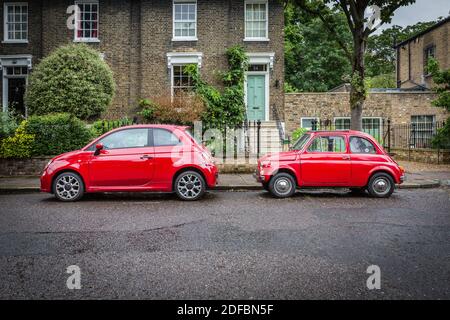 Due generazioni della Fiat 500 nello stesso colore rosso parcheggiarono lungo una verde strada londinese. Foto Stock