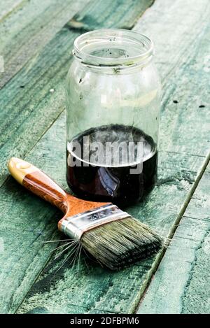 Pennello e vaso di vernice su tavola di legno Foto Stock