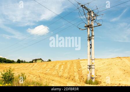 Linee di alimentazione ad alta tensione su campo contro con cielo blu Foto Stock