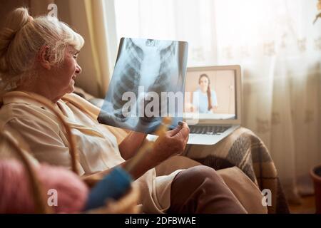 Donna anziana che ha consultazione in linea con il medico a casa Foto Stock