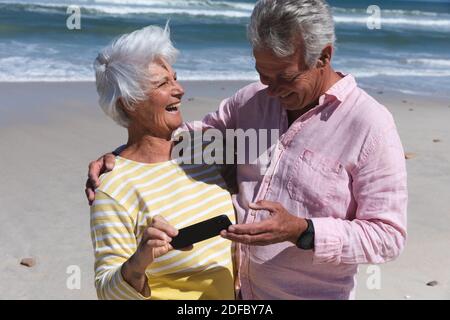 Coppia caucasica senior sulla spiaggia vicino al mare con smartphone Foto Stock